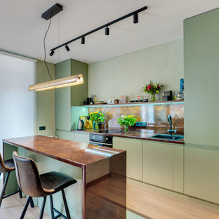 На фото: прямая кухня в современном стиле с накладной раковиной, плоскими фасадами, зелеными фасадами, коричневым фартуком, черной техникой, островом, бежевым полом и коричневой столешницей с