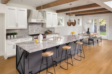 Example of a mid-sized farmhouse single-wall light wood floor and brown floor eat-in kitchen design in Houston with an undermount sink, recessed-panel cabinets, white cabinets, granite countertops, gray backsplash, porcelain backsplash, an island and gray countertops