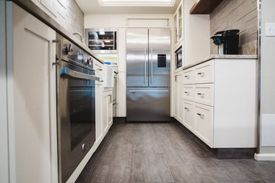 Inspiration for a small transitional galley ceramic tile enclosed kitchen remodel in Seattle with an undermount sink, shaker cabinets, white cabinets, beige backsplash, ceramic backsplash, stainless steel appliances and no island
