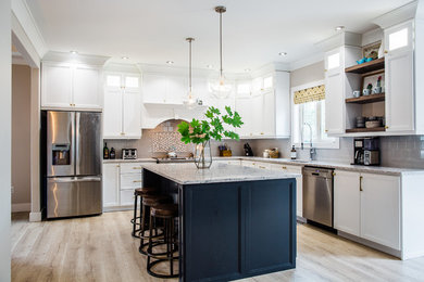 Kitchen - transitional light wood floor and brown floor kitchen idea in Toronto with an undermount sink, recessed-panel cabinets, white cabinets, gray backsplash, stainless steel appliances, an island and gray countertops