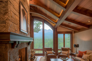 Example of a large mountain style open concept dark wood floor and brown floor family room design in Denver with beige walls, a two-sided fireplace and a stone fireplace