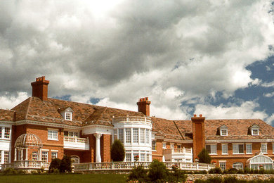 Inspiration for a huge timeless red two-story brick house exterior remodel in Boston with a hip roof and a shingle roof