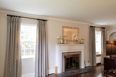 This is an example of a mid-sized traditional enclosed living room in New York with beige walls, medium hardwood floors, a standard fireplace, a tile fireplace surround, no tv and brown floor.