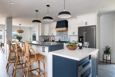 Kitchen - contemporary u-shaped laminate floor and brown floor kitchen idea in Orange County with a farmhouse sink, shaker cabinets, blue cabinets, soapstone countertops, white backsplash, ceramic backsplash, stainless steel appliances, an island and multicolored countertops