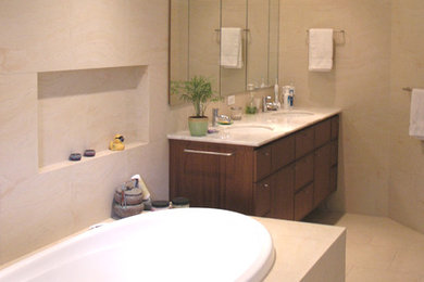 Example of a trendy master beige tile and porcelain tile porcelain tile drop-in bathtub design in Philadelphia with an undermount sink, flat-panel cabinets, medium tone wood cabinets, beige walls and marble countertops