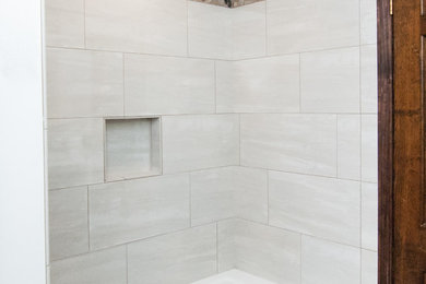 This is an example of a traditional bathroom in Milwaukee with recessed-panel cabinets, medium wood cabinets, an alcove tub, a shower/bathtub combo, gray tile, white walls, porcelain floors, an integrated sink, beige floor, a shower curtain and white benchtops.