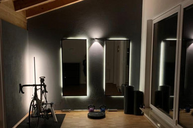 Kleiner Skandinavischer Yogaraum mit schwarzer Wandfarbe, braunem Holzboden und braunem Boden