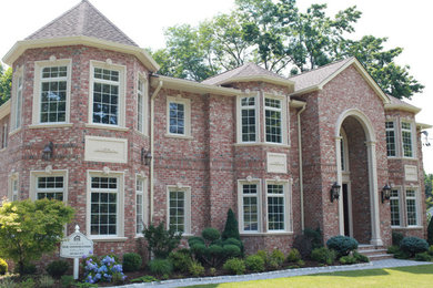 Inspiration for a large timeless red two-story brick exterior home remodel in New York