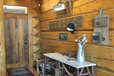 Example of a mid-sized mountain style medium tone wood floor, brown floor, exposed beam and wood wall entryway design in Denver with brown walls and a medium wood front door