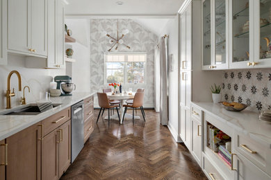 Example of a transitional galley medium tone wood floor, brown floor, vaulted ceiling and wallpaper ceiling eat-in kitchen design in Other with an undermount sink, shaker cabinets, quartz countertops, quartz backsplash, stainless steel appliances, white cabinets, multicolored backsplash, no island and white countertops