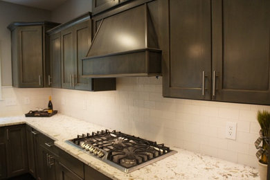 Transitional u-shaped eat-in kitchen photo in Other with a farmhouse sink, flat-panel cabinets, white backsplash, ceramic backsplash, stainless steel appliances and an island