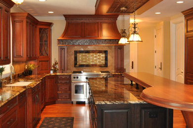 Example of a large classic l-shaped medium tone wood floor and red floor open concept kitchen design in Denver with a farmhouse sink, beaded inset cabinets, dark wood cabinets, granite countertops, multicolored backsplash, ceramic backsplash, stainless steel appliances, two islands and multicolored countertops