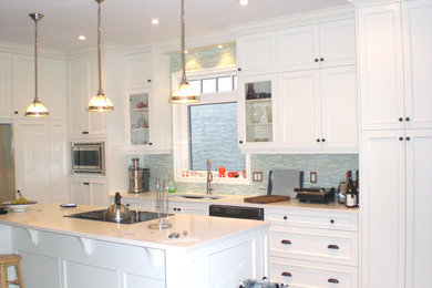 This is an example of a medium sized classic l-shaped kitchen/diner in Calgary with recessed-panel cabinets, white cabinets, onyx worktops, glass tiled splashback, stainless steel appliances and an island.