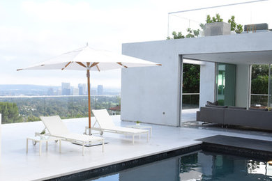 Photo of a large contemporary rooftop rectangular pool in Los Angeles with concrete slab.