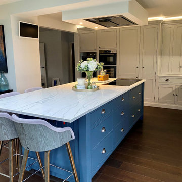 Dark blue kitchen island with white cabinets and integrated hob