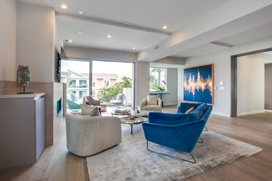 Inspiration for a mid-sized modern open concept light wood floor and brown floor family room remodel in Los Angeles with white walls, a standard fireplace, a tile fireplace and a wall-mounted tv