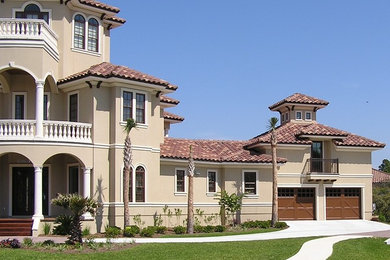 Large mediterranean beige three-story stucco exterior home idea in Miami with a hip roof