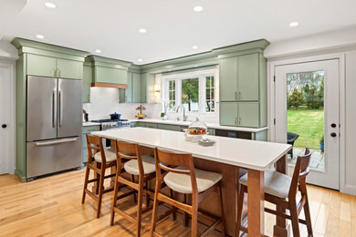 Open concept kitchen - mid-sized transitional l-shaped medium tone wood floor open concept kitchen idea in Philadelphia with an undermount sink, shaker cabinets, green cabinets, quartzite countertops, white backsplash, stainless steel appliances, an island and white countertops