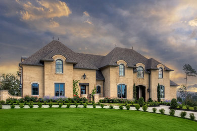 Inspiration for a large timeless beige two-story brick house exterior remodel in Little Rock with a shingle roof