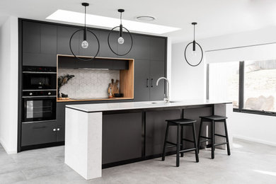 Inspiration for a modern galley kitchen in Hobart with with island, a double-bowl sink, flat-panel cabinets, black cabinets, white splashback, panelled appliances, concrete floors, grey floor and white benchtop.