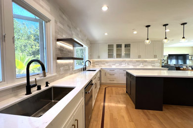 Inspiration for a large transitional u-shaped medium tone wood floor and yellow floor eat-in kitchen remodel in San Francisco with an undermount sink, shaker cabinets, white cabinets, quartz countertops, gray backsplash, ceramic backsplash, stainless steel appliances, an island and white countertops