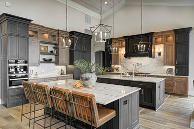 This is an example of a mid-sized contemporary galley eat-in kitchen in Indianapolis with shaker cabinets, medium wood cabinets, marble benchtops, white splashback, marble splashback, stainless steel appliances, medium hardwood floors, multiple islands, white benchtop, wood and brown floor.
