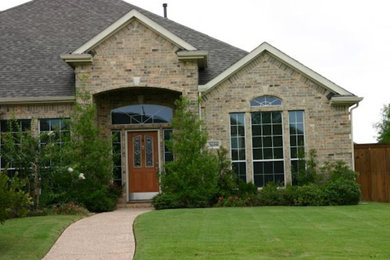 This is an example of a mid-sized traditional brick beige house exterior in Dallas with a gable roof and a shingle roof.