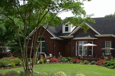 Photo of a large traditional one-storey brick red house exterior in Charleston with a gable roof and a shingle roof.