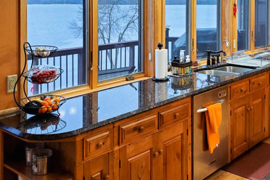 Example of a large mountain style single-wall light wood floor and beige floor eat-in kitchen design in Chicago with glass-front cabinets, medium tone wood cabinets, marble countertops, stone tile backsplash, stainless steel appliances and black countertops
