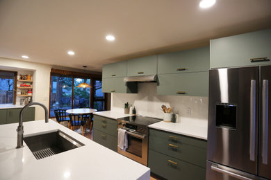 Example of a mid-sized 1950s light wood floor eat-in kitchen design in Portland with an undermount sink, flat-panel cabinets, green cabinets, quartz countertops, white backsplash, subway tile backsplash, stainless steel appliances, an island and white countertops