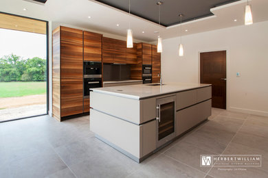 Ejemplo de cocina contemporánea grande con armarios con paneles lisos, puertas de armario de madera oscura, encimera de cuarcita, electrodomésticos de acero inoxidable y una isla