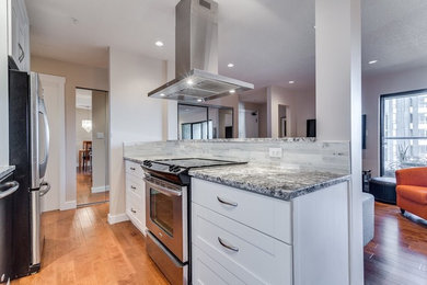 Inspiration for a mid-sized modern galley medium tone wood floor eat-in kitchen remodel in Vancouver with a single-bowl sink, recessed-panel cabinets, white cabinets, granite countertops, gray backsplash, stone slab backsplash and stainless steel appliances