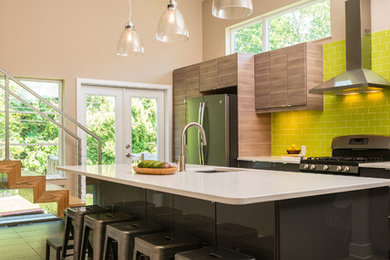 Mid-sized contemporary galley open plan kitchen in Philadelphia with an undermount sink, flat-panel cabinets, black cabinets, green splashback, subway tile splashback, stainless steel appliances, with island, brown floor, quartz benchtops and ceramic floors.