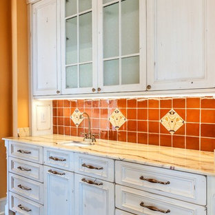 マイアミの中サイズの地中海スタイルのおしゃれなウェットバー (アンダーカウンターシンク、家具調キャビネット、ヴィンテージ仕上げキャビネット、オニキスカウンター、オレンジのキッチンパネル、テラコッタタイルのキッチンパネル、無垢フローリング、マルチカラーのキッチンカウンター) の写真