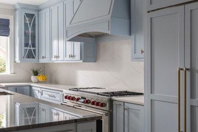 Large transitional l-shaped medium tone wood floor eat-in kitchen photo in Charlotte with a farmhouse sink, shaker cabinets, blue cabinets, white backsplash, paneled appliances, an island and white countertops