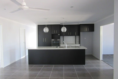 This is an example of a mid-sized modern galley eat-in kitchen in Brisbane with a double-bowl sink, dark wood cabinets, laminate benchtops, white splashback, cement tile splashback, stainless steel appliances, ceramic floors and with island.