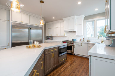Example of a large transitional u-shaped medium tone wood floor and brown floor eat-in kitchen design in Chicago with an undermount sink, shaker cabinets, white cabinets, quartz countertops, white backsplash, porcelain backsplash, stainless steel appliances, an island and white countertops