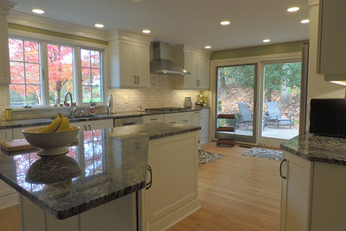 Kitchen - transitional light wood floor kitchen idea in Other with a single-bowl sink, shaker cabinets, white cabinets, granite countertops, white backsplash, ceramic backsplash, stainless steel appliances, an island and black countertops
