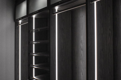 Mid-sized trendy gender-neutral beige floor walk-in closet photo in Miami with flat-panel cabinets and dark wood cabinets