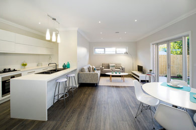 This is an example of a mid-sized contemporary single-wall eat-in kitchen in Melbourne with a double-bowl sink, recessed-panel cabinets, white cabinets, soapstone benchtops, white splashback, ceramic splashback, stainless steel appliances, dark hardwood floors and with island.