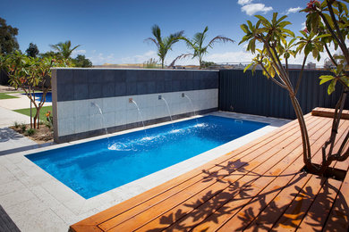 Photo of a large contemporary side yard rectangular natural pool in Perth with a water feature and natural stone pavers.
