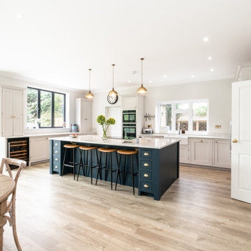Stunning white kitchen with large dark blue island and marble worktops