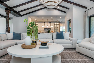 Example of a large beach style open concept painted wood floor and exposed beam living room design in Miami with a bar