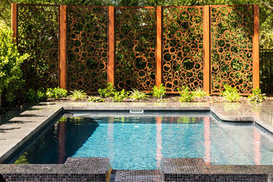 Mid-sized contemporary backyard rectangular pool in Melbourne with natural stone pavers and a hot tub.