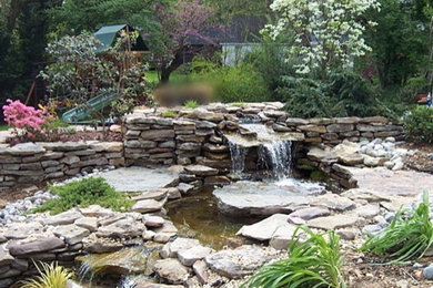Diseño de jardín tradicional grande en patio trasero con fuente, exposición parcial al sol y adoquines de piedra natural