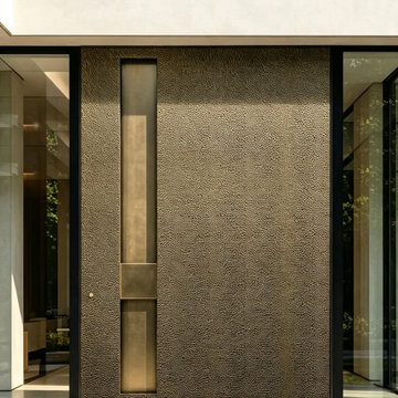 Monumental Textured Metal Pivot Entry Door