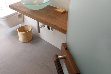 Bathroom - mid-sized modern 3/4 gray tile and porcelain tile concrete floor and gray floor bathroom idea in Vancouver with wood countertops, open cabinets, dark wood cabinets, a wall-mount toilet, gray walls, a vessel sink and brown countertops