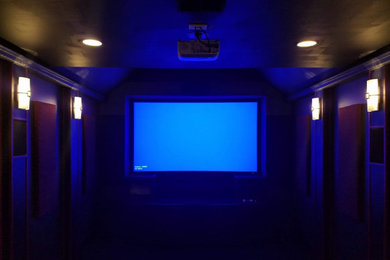 Inspiration for a carpeted home theater remodel in Other with black walls and a media wall