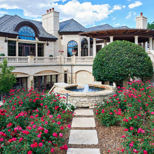 Aménagement d'un jardin arrière méditerranéen avec un point d'eau, une exposition ensoleillée et des pavés en pierre naturelle.