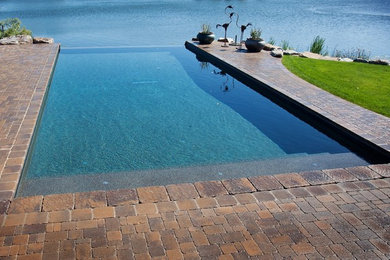 Mid-sized traditional backyard rectangular infinity pool in Boise with brick pavers.